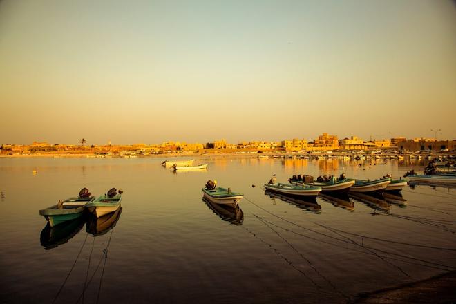 View of boats on the sea with the town of Salalah in the background