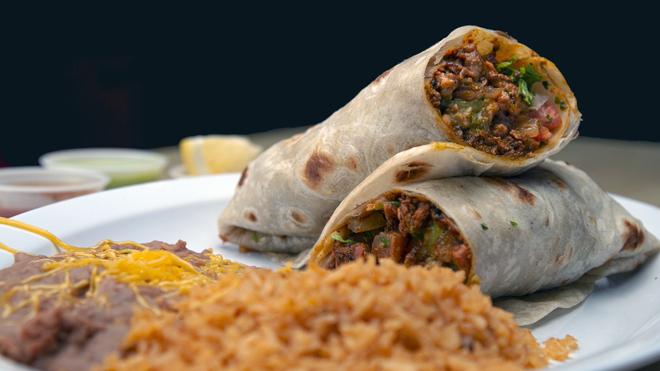2 pieces of Mexican burritos on a plate: rolled tortillas are filled with a mixture of beans, minced meat, cheese and peppers.