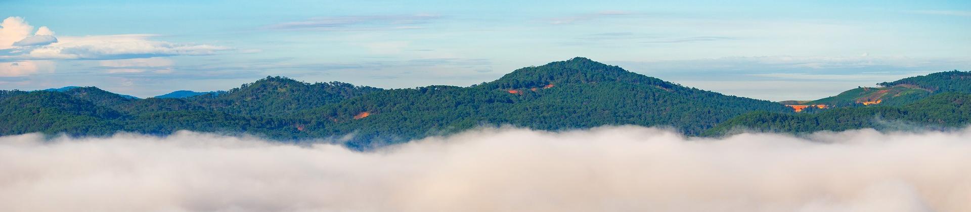 Aerial view of mountain range in Da Lat in sunny weather with few clouds