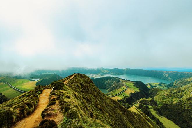 The hilly, misty landscape of the Azores with a hiking trail.