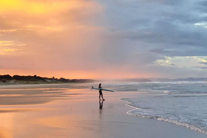 A surfer on a beach in New Zealand