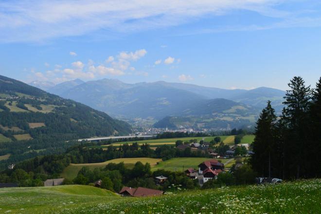 View of cotagges in the hills, forest and mountains in the background in Nockberge