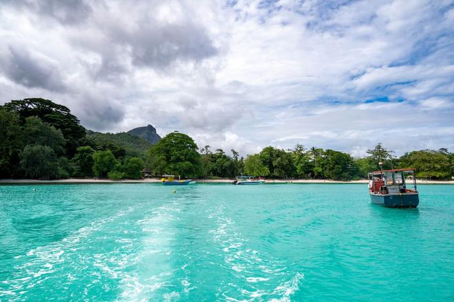 Boats on turquoise sea, beaches, and forests on Mahé Island