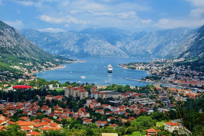 An aerial view of the city of Kotor surrounded by nature, sea, and mountains in the background