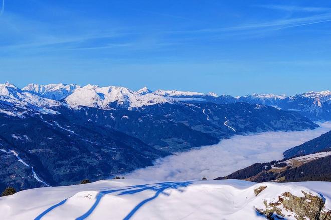 View of snowy mountain peaks surrounded by clouds in Zell am Ziller