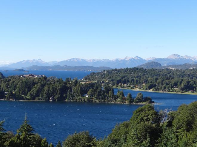 View of the lake in clear weather near San Carlos de Bariloche, Patagonia in Argentina with deep blue water and surrounding forest.