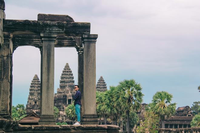 Cambodia: Angkor Wat: temple gate with tourist, temple and palm trees.