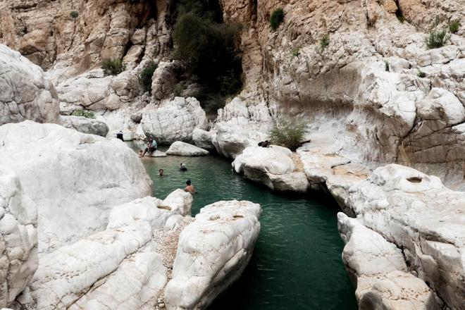 People swimming in a river surrounded by rocks in Wadi Bani Khalid