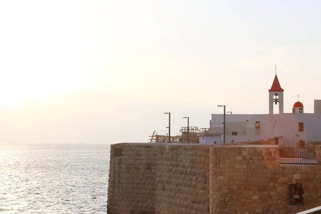 A building with a clock surrounded by walls and sea in Akko city, Israel