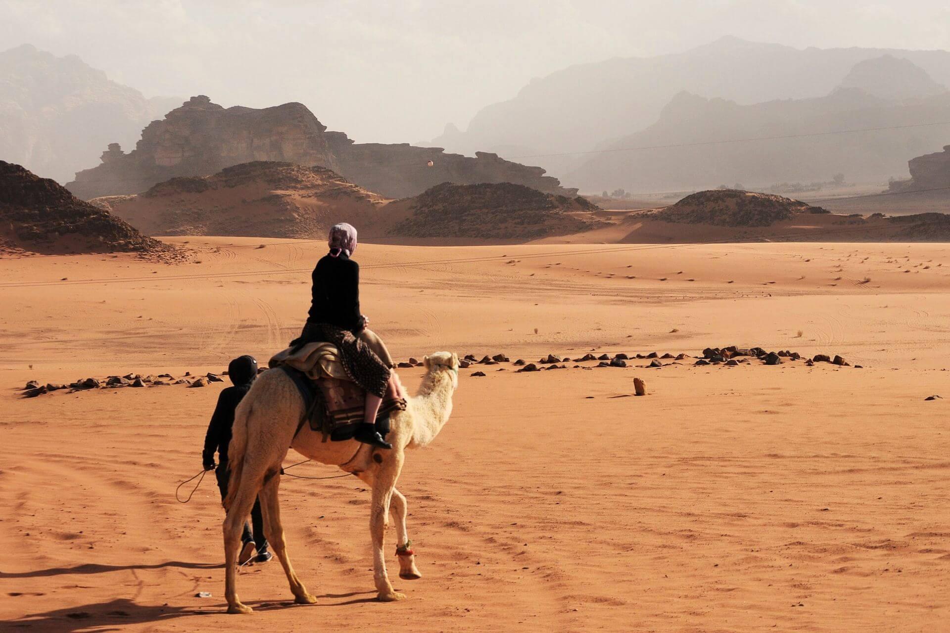 A person riding a camel in a desert in Jordan