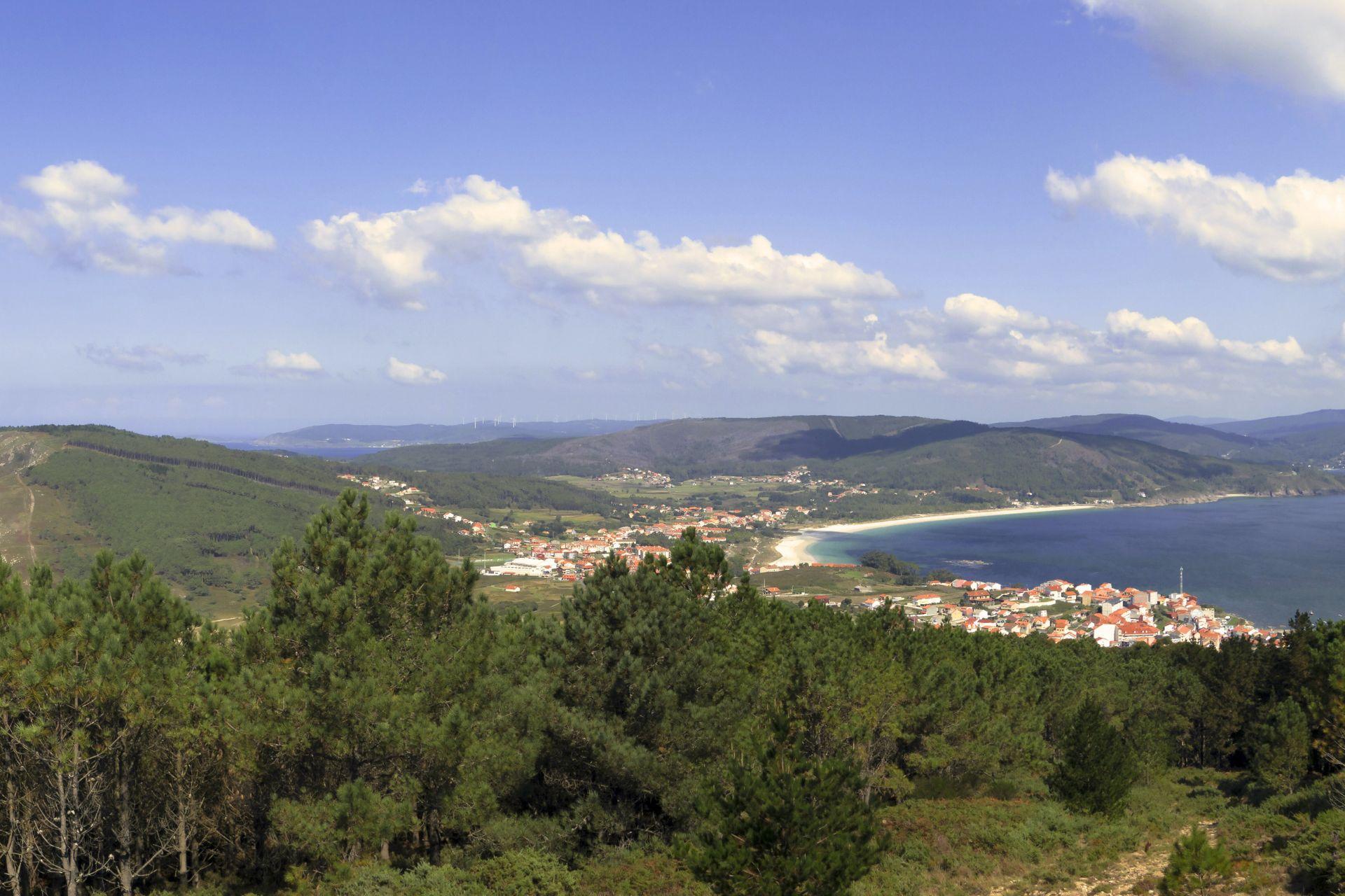 View of mountains covered with forrest and city surrounded by the sea in the background