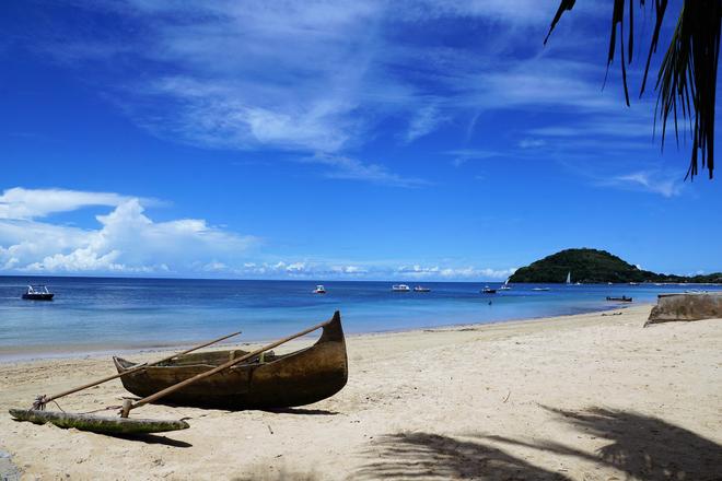 Beach with wooden boat and blue sea in Madagascar.