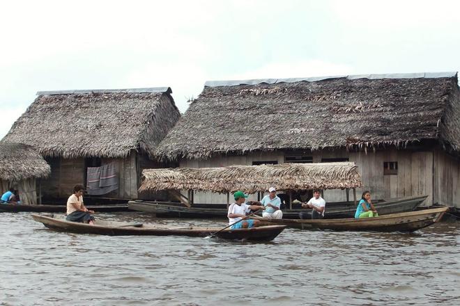 People sailing boats next to houses surrounded by lake