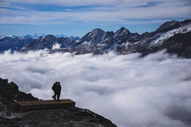 View of tourists admiring a view of mountain peaks and clouds in Fieschertal, Switzerald