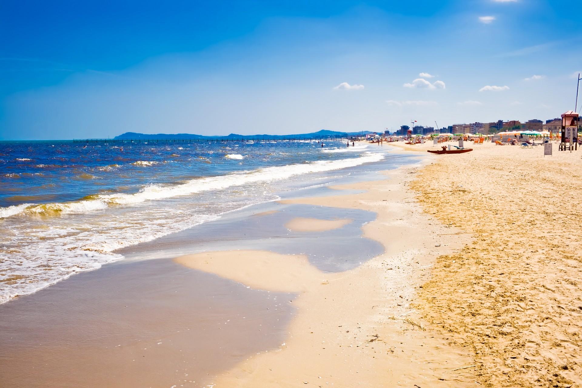 People on the beach and boat in Rimini in partly cloudy weather