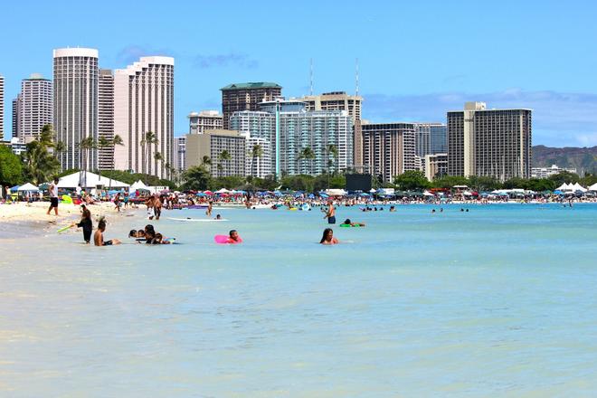Hawaii, Waikiki Beach: people on the beach and in the sea with skyscrapers in the background.