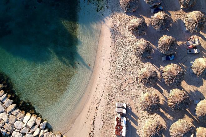 Sunshades on a beach surrounded be the sea and rocks in Negril, Jamaica