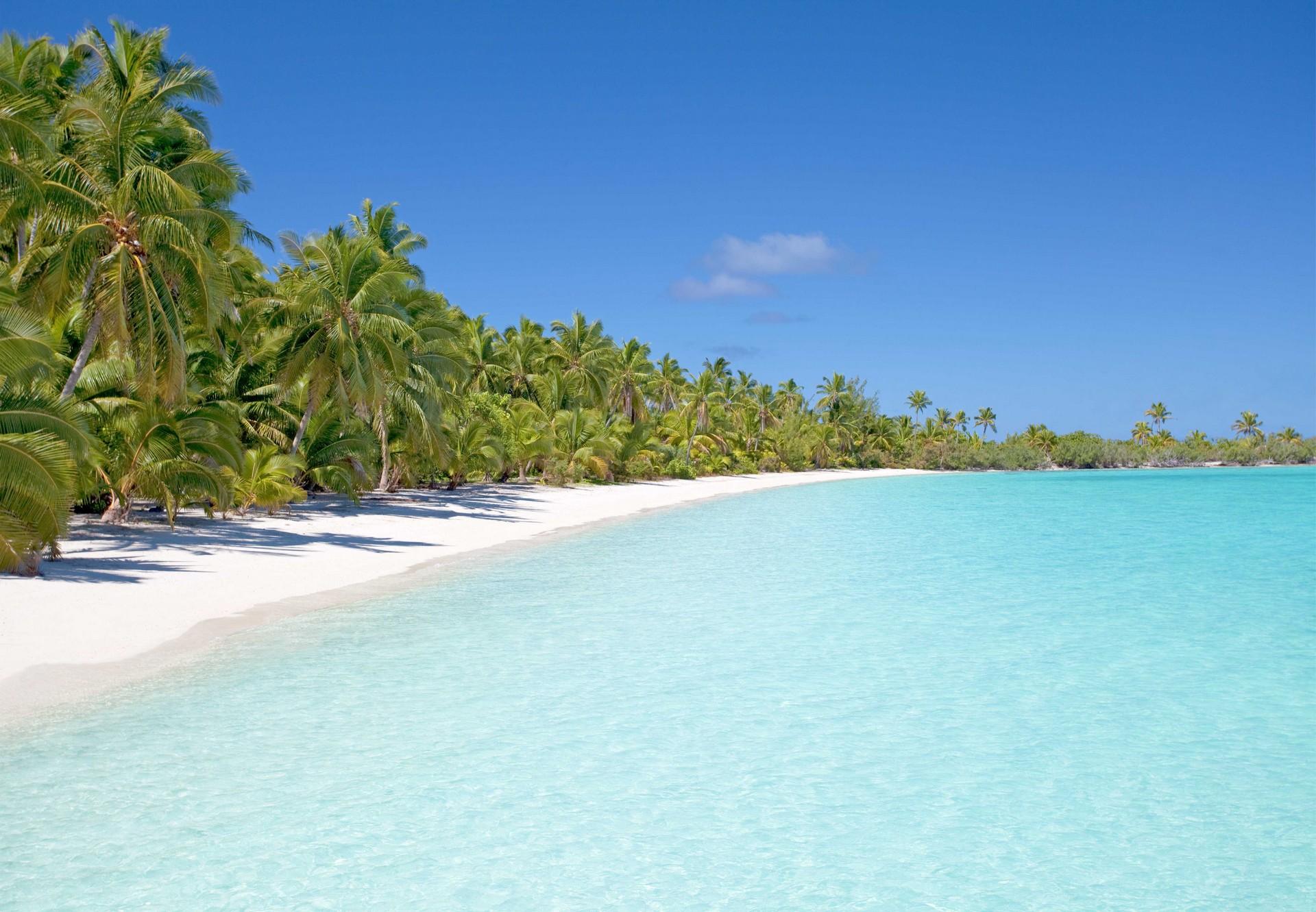 Nice beach by the sea with turquise water in Aitutaki on a clear sky day