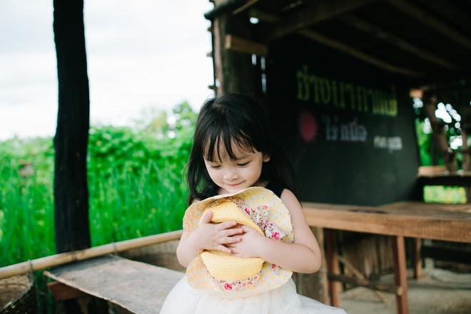 Mae Hong Son in Thailand: little girl sitting on a bench near a meadow.