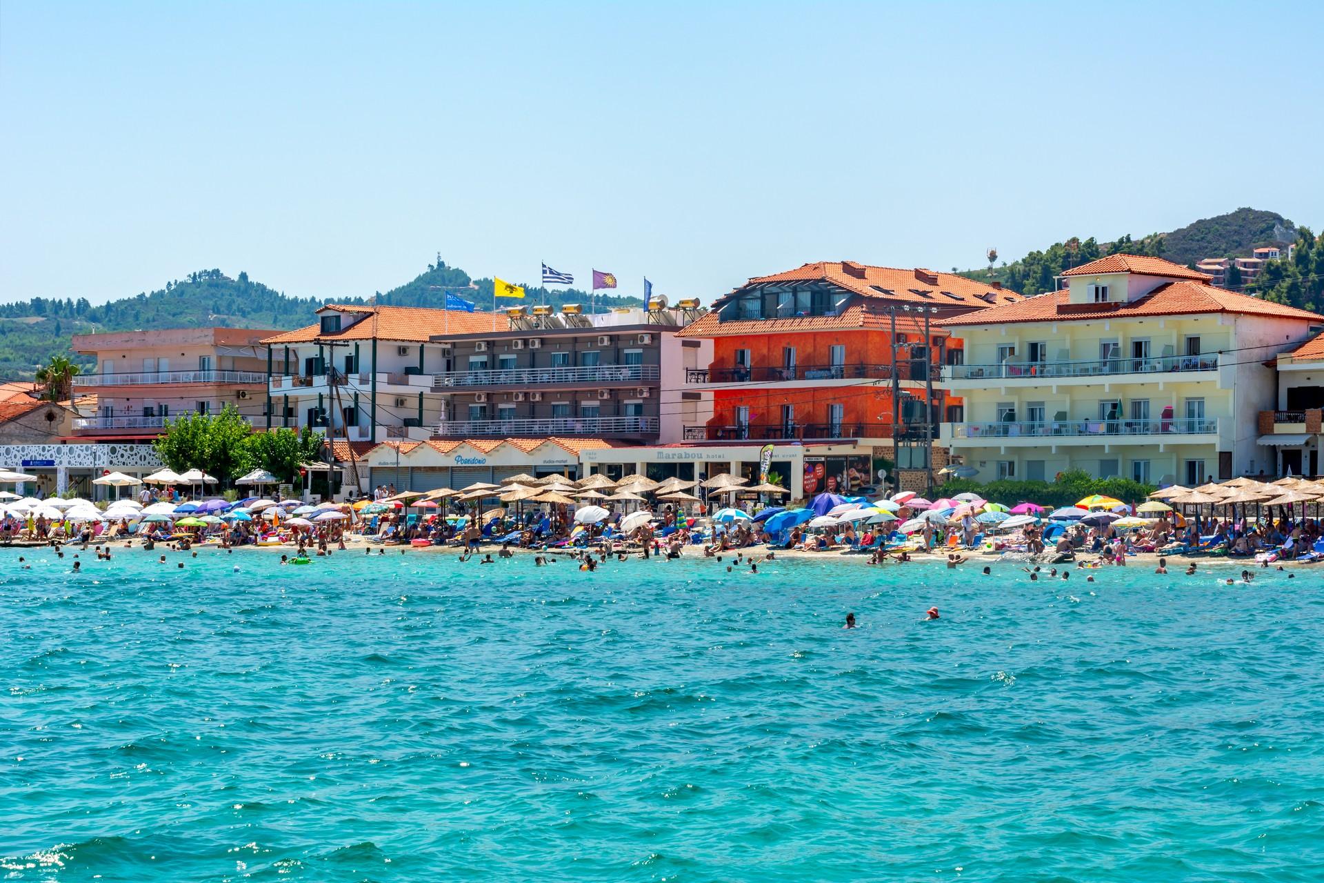 People on the beach and port in Pefkochóri on a sunny day