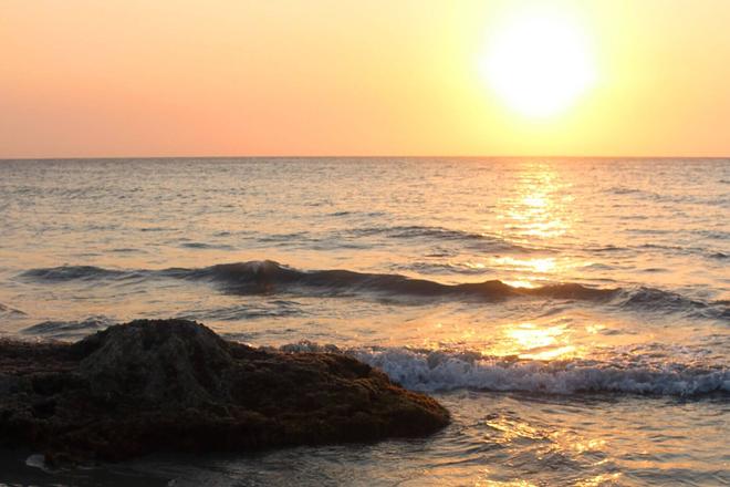 View of a sunset, beach, sea and a rock formation in Tayrona, Colombia