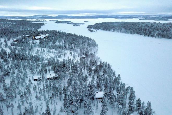View of a snowy landscape covered with forests and a few cottages, Lapland