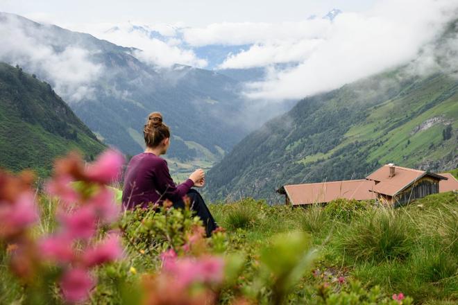 View of a woman sitting in the Austrian Alps and enjoying the beautiful view of mountains and nature