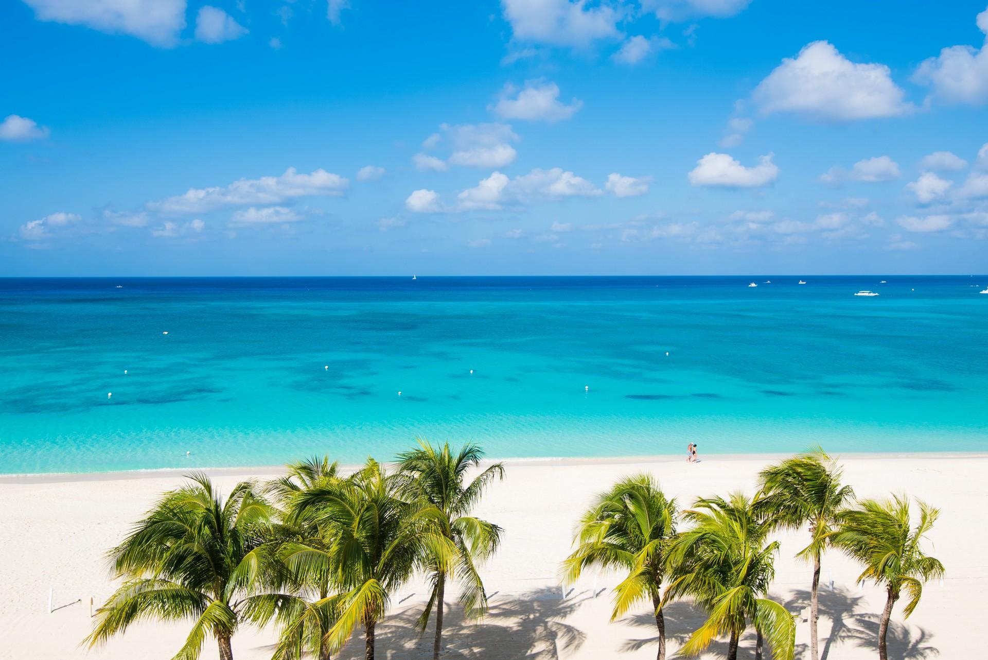 Enjoyable beach with turquise water in Grand Cayman on a sunny day with some clouds