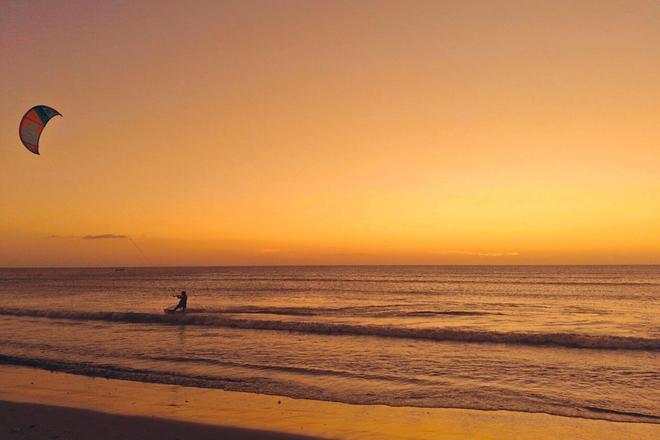 Person kiteboarding in the sea at sunset