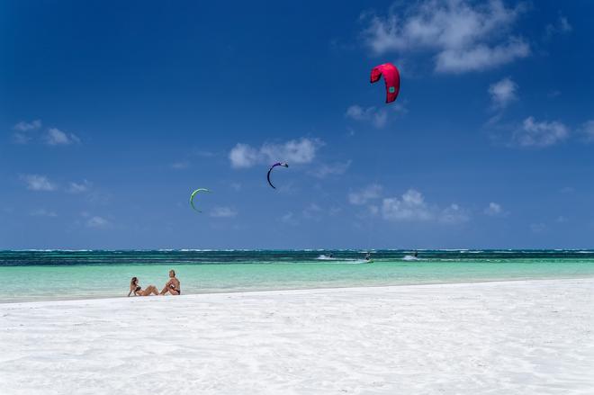 Watamu, Kenya: women on the white beach and kite surfers in the background