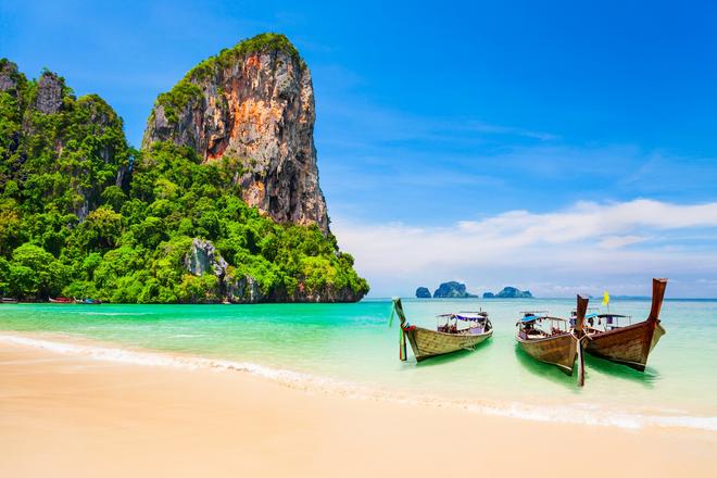 Beautiful beach on Ko Phi Phi Island with rock and two boats.