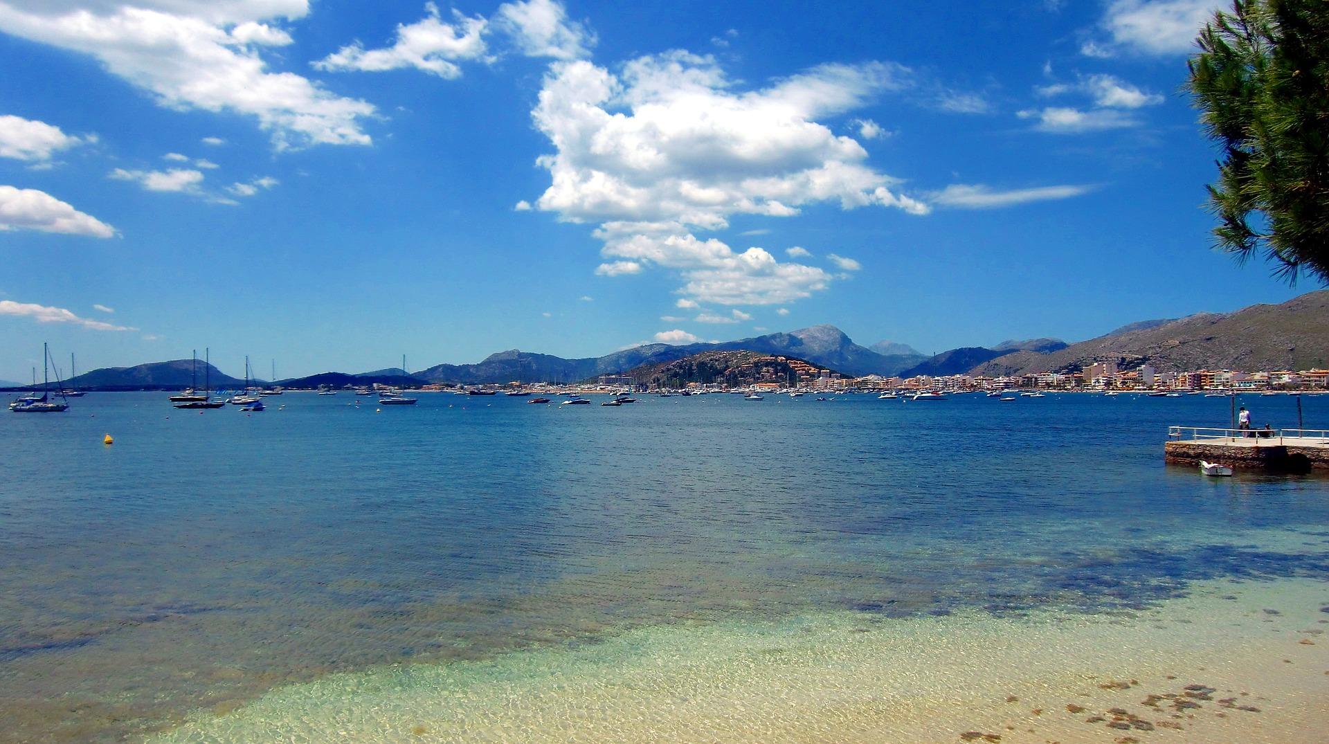 Beach and mountain range near Port de Pollença on a sunny day with some clouds