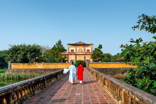 Two women walking on a bridge that leads to a temple in Hue City, Vietnam