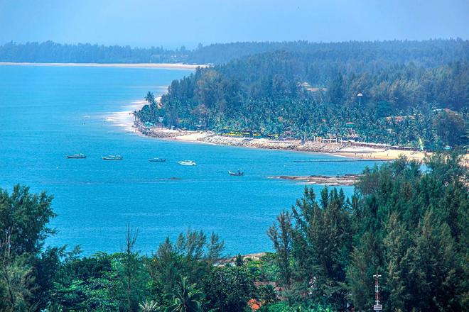 View of a forest, beach and a sea with boats