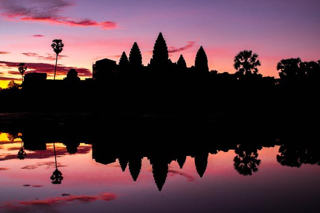 Cambodia, Angkor Wat at sunset with pink and purple sky.