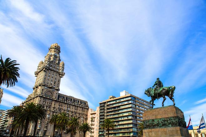 Partly cloudy sky over the centre of Montevideo (Uruguay) with a statue and palm trees.  