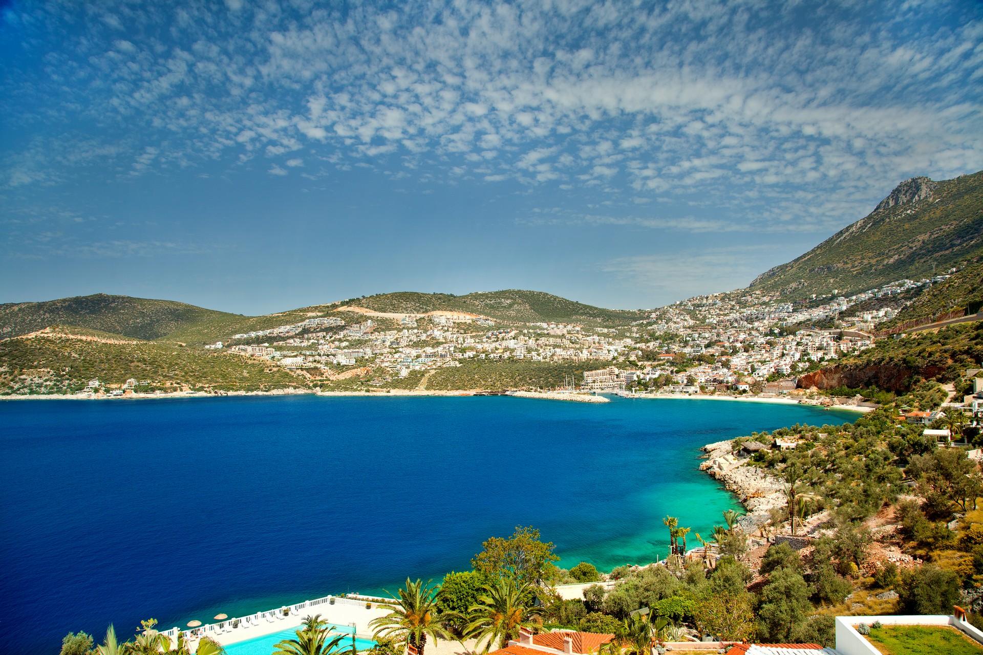 Beach with turquise water in Kalkan on a sunny day with some clouds