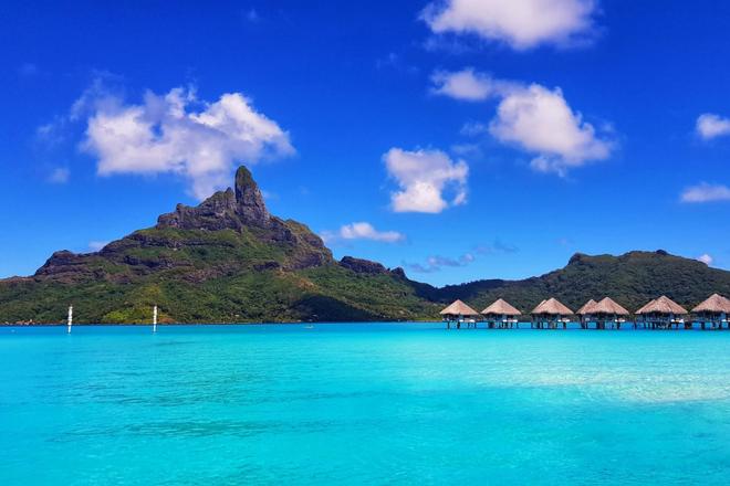 Overwater bungalows next to the island of Bora Bora and the sea