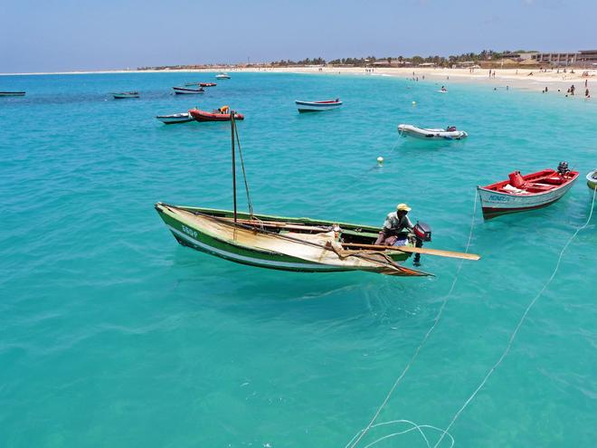Cabo Verde fishermen on boats on the turquoise sea in clear skies.