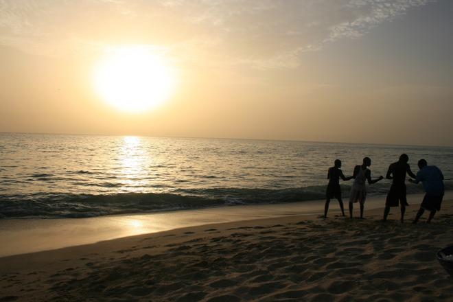 Boys playing in sunset on the calm beach in Senegal.