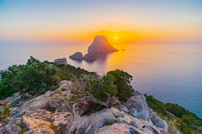 Sunset over Ibiza with a rocj in the sea.