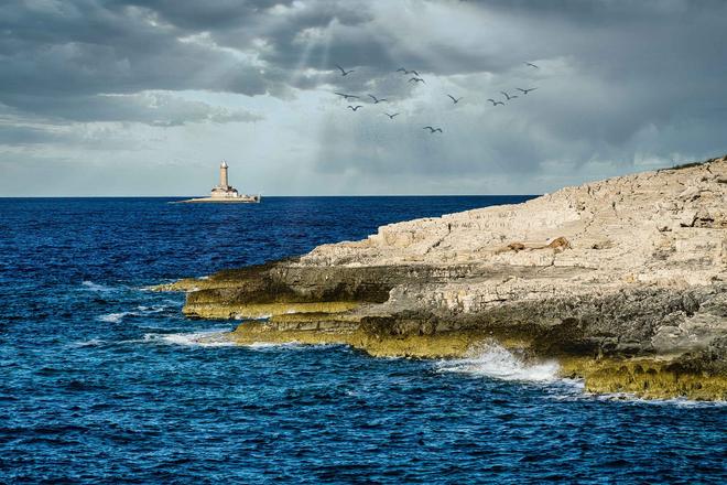 Kamenjak peninsula, Croatia: rocky outcrop and a lighthouse in the background.