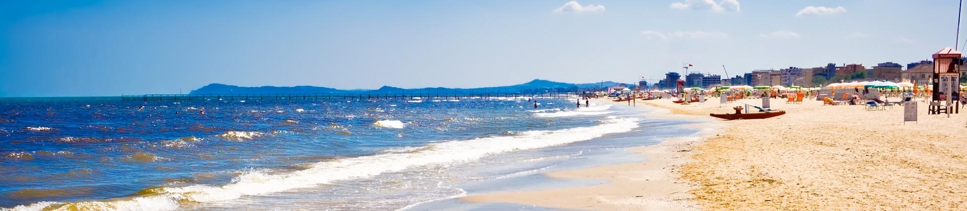 People on the beach and boat in Rimini in partly cloudy weather