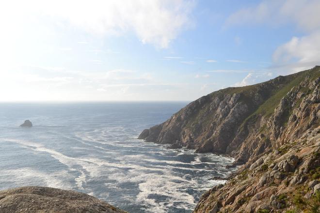 View of coast mountains surrounded by the sea in Fisterra