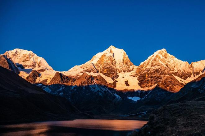 View of a lake surrounded by Huayhuash mountains covered with snow in Peru