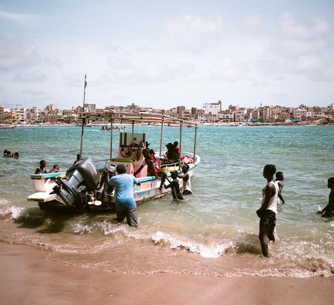 A small boat leaving the coast with people.