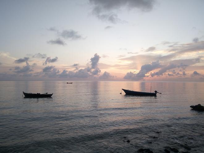 Boats at sea at sunset in the Maldives.