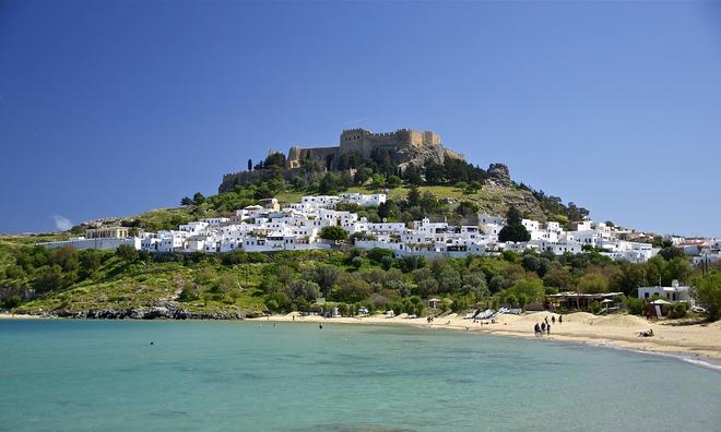 Village with a beach by the sea with a castle on the hill in Rhodes.
