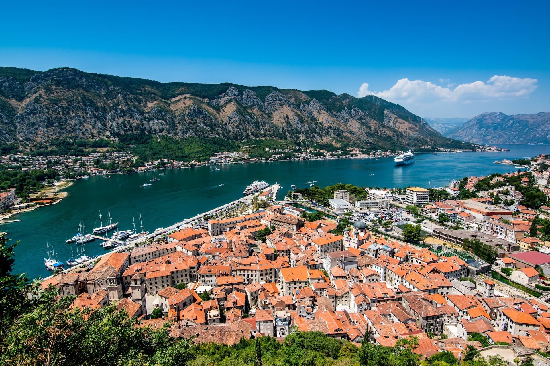 An aerial view of the city of Kotor, sea and boats and mountains in the background