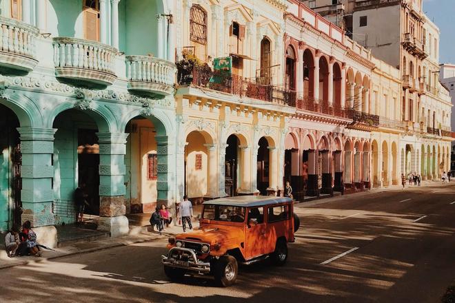 View of colorful houses, car, road and people in Holguín